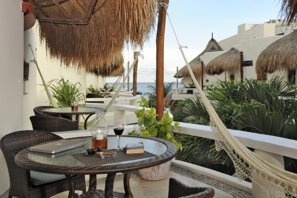 Stuga-halmtak-balkong-bord-med-stolar-hängmatta-utsikt-över-havet