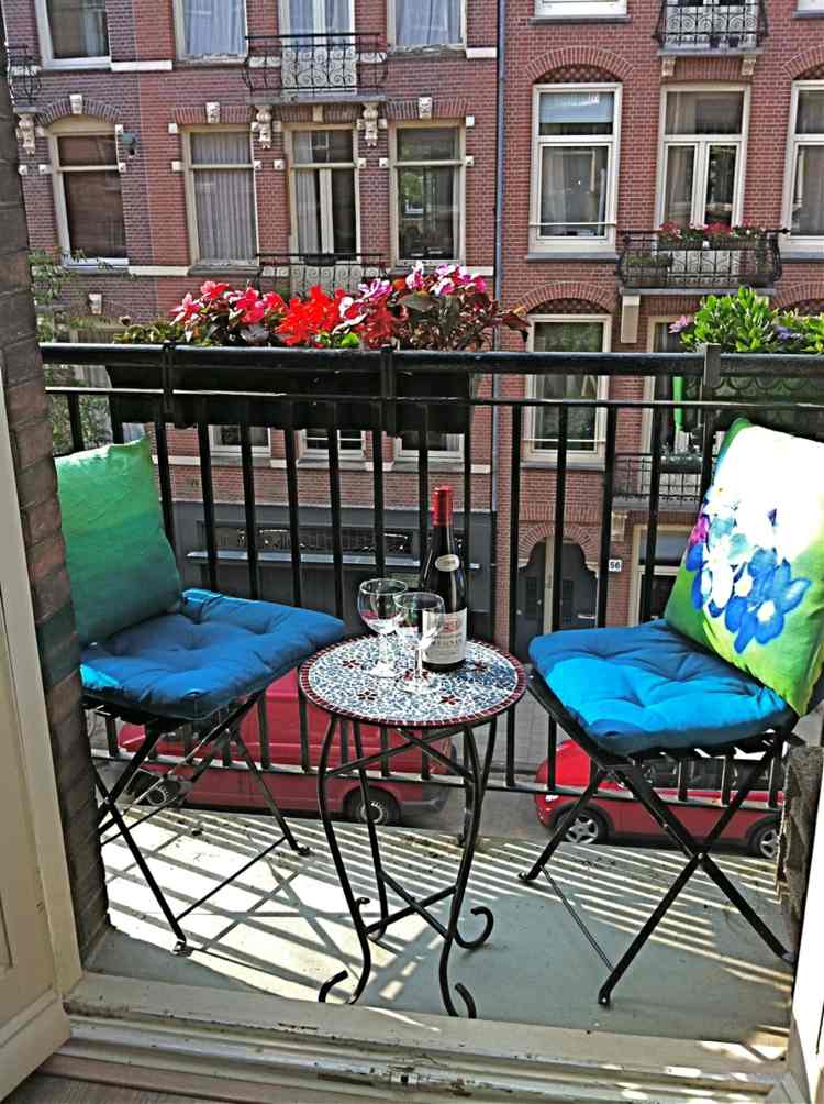 balkong i sommar sittdyna blå grön metall möbler räcke blomlåda