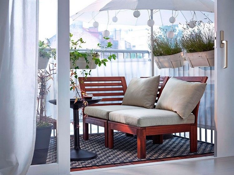 smal terrass med soffa, matta, växter, paraply och bord