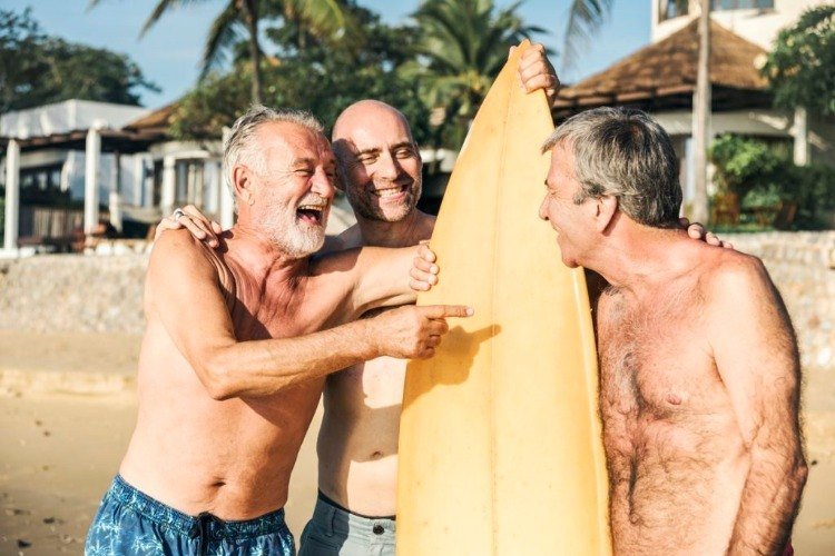 Äldre män vänner på semester skrattar med surf