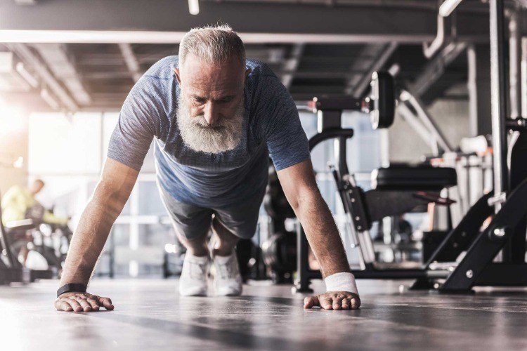 Skäggig man gör armhävningar i gymmage som tränar män över 50