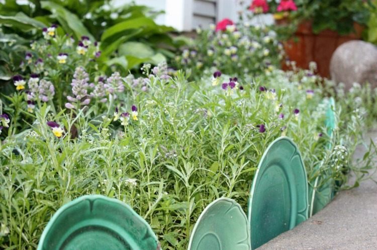 grönt porslin arrangerat som en trädgårdsgräns på trädgårdsvägen framför växter