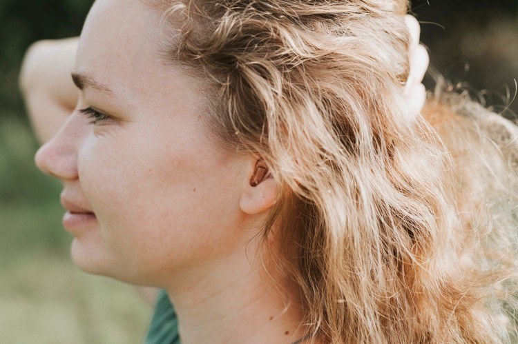 Kvinna med in-ear-hörapparat tips om hur man hör bättre