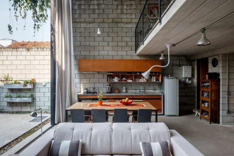 betong-design-modernt-öppet-kök-trä-fronter-soffa-ljus-grå-fönster-vägglampor-industriell-stil-katt