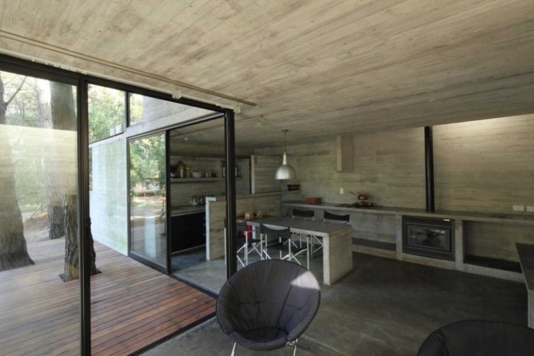 betong-design-modern-exponerad betong-fönster-altandörrar-fåtölj-öppna-rum-hylla-öppen spis-bord
