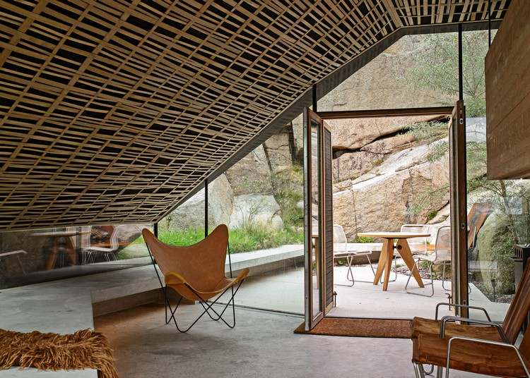 betong-glas-semesterhus-interiör-sluttande tak-läderfåtölj
