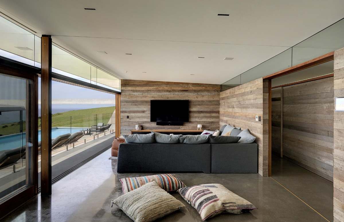 modernt designat vardagsrum med träväggar, skjutdörrar i glas och betonggolv