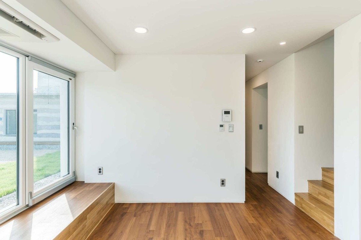 minimalistiskt rum med trägolv och vita väggar samt trapp- och takbelysning