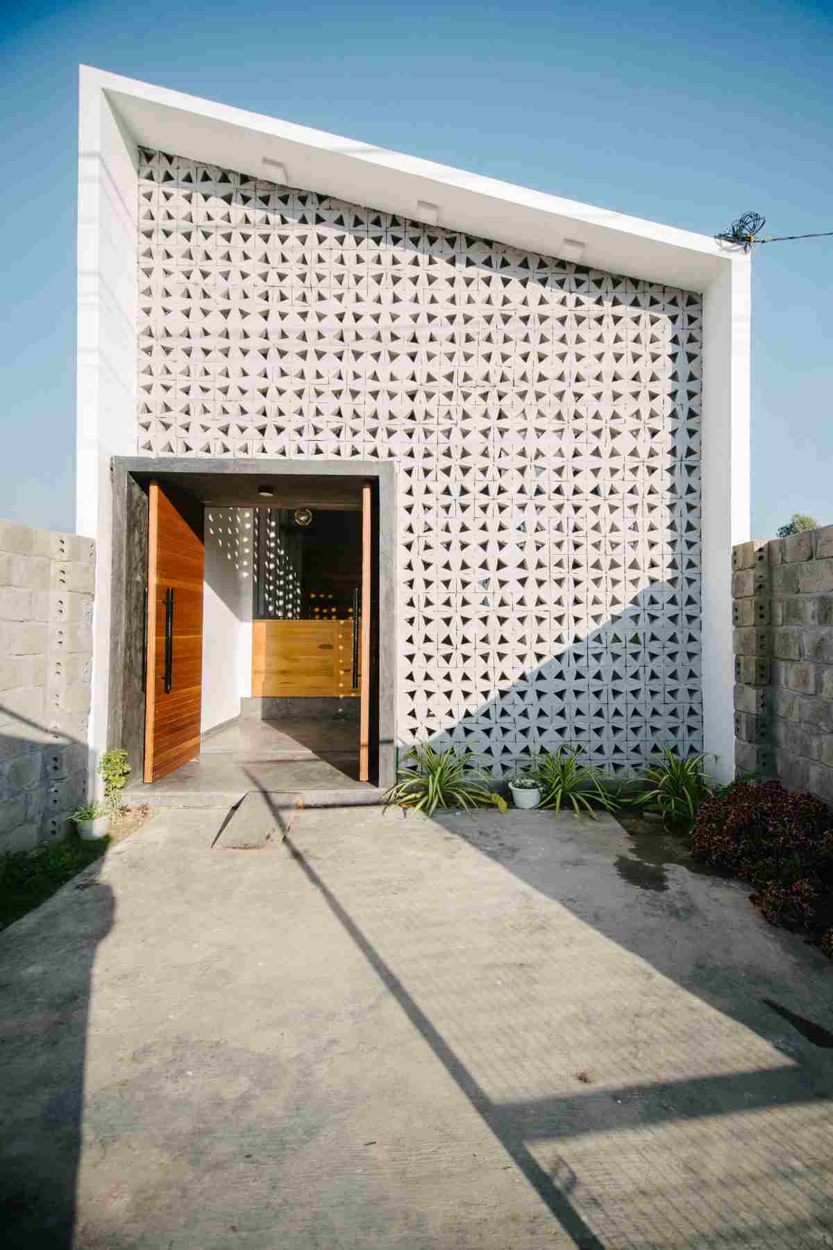 hus kontum med en fasad av genomskinliga betongblock och en förgård och ett sluttande tak