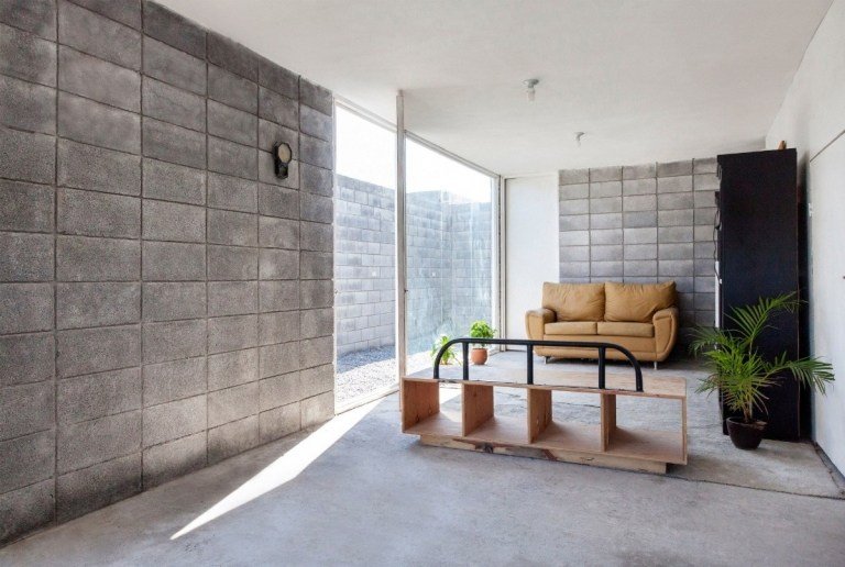 billigt byggt hus med minimalistiskt vardagsrum och väggar av betongblock