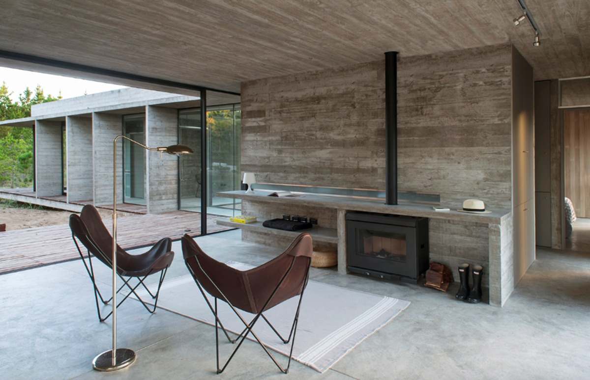 öppet vardagsrum med öppen spis och designerstolar med betonggolv och tak