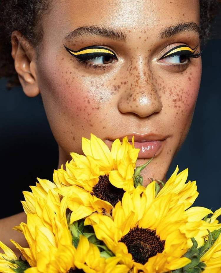 lady bee som applicerar smink diskret blommor eyeliner gul svart