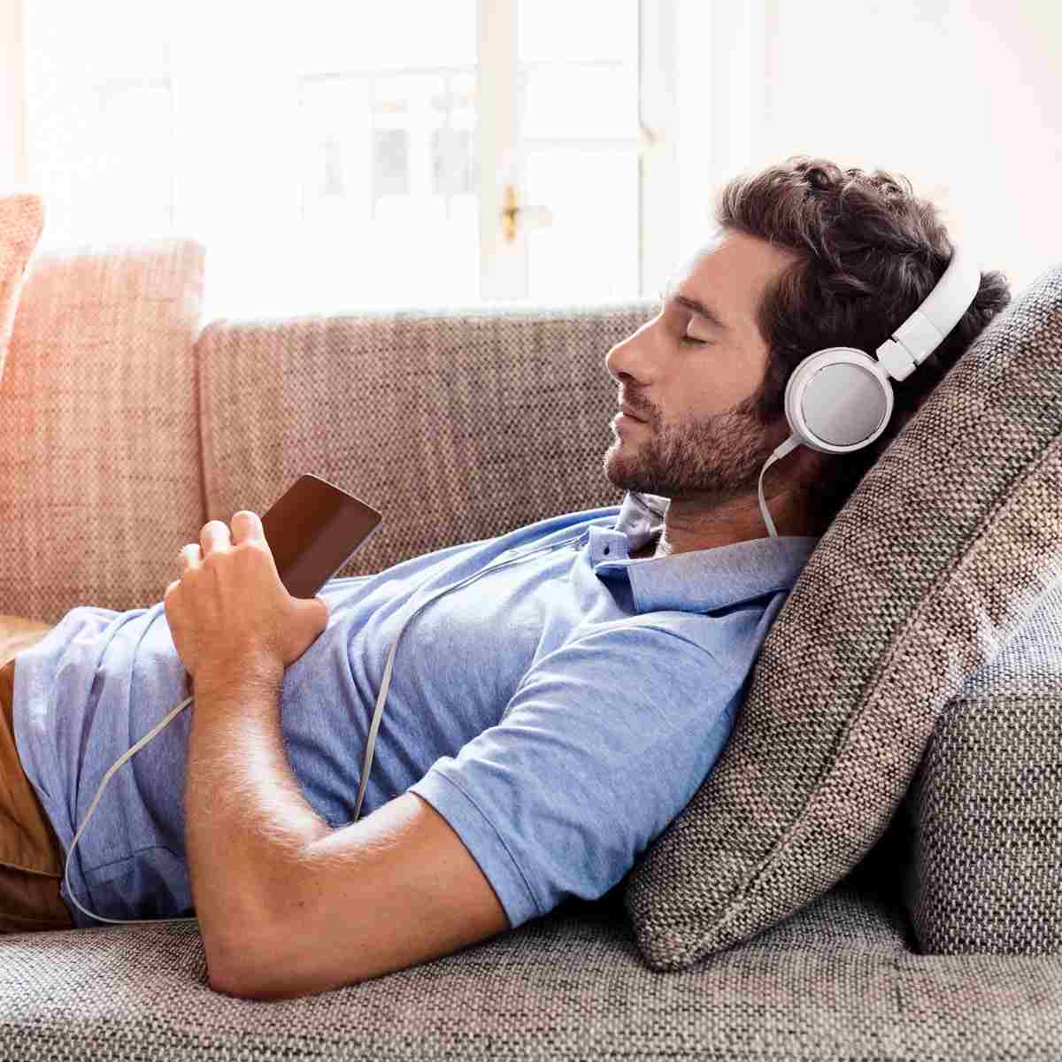 koppla av i soffan med hörlurar hemma och minska stressen