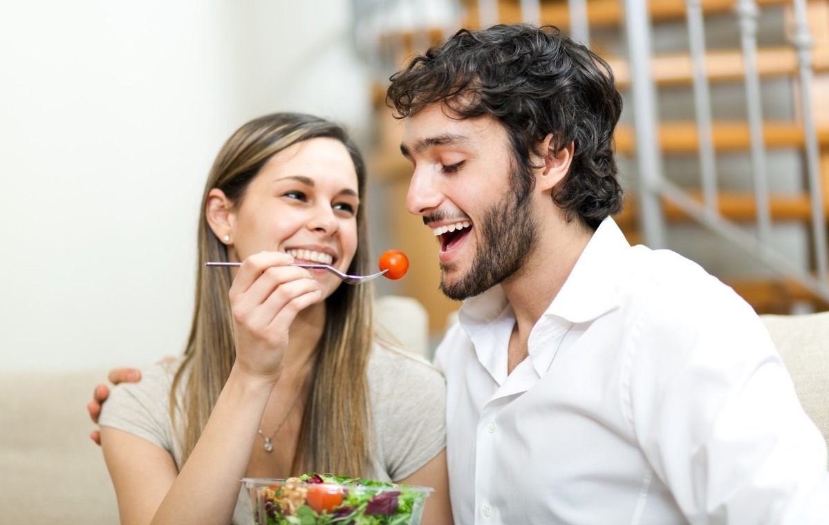 kvinna räcker sin partner körsbärstomater från salladsskålen för bättre kolhydratabsorption