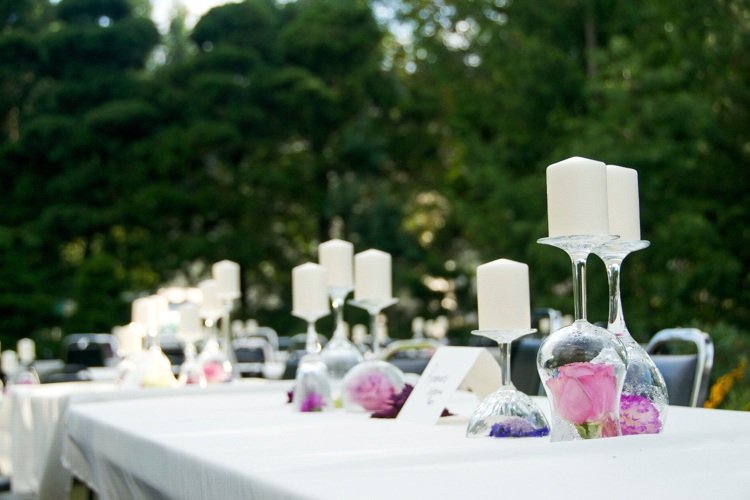 Blomsterdekoration i ett vinglas, ljushållare, rosenblad, bröllopsborddekoration