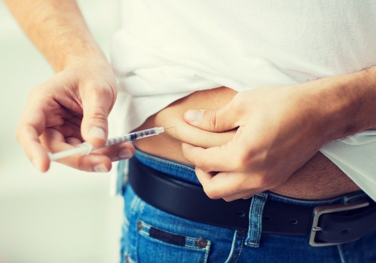 mannen håller i magen och injicerar insulin på grund av diabetes