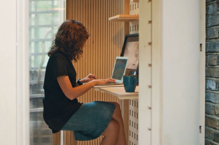 kvinna som använder bärbar dator medan hon sitter och arbetar på hemmakontoret utanför på den smala innergården