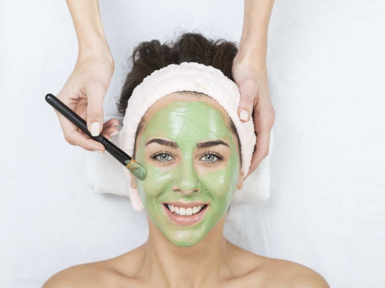 le kvinna hos kosmetologen har ansiktet behandlat med vattenkrasse ansiktsmask för frisk hud och hår