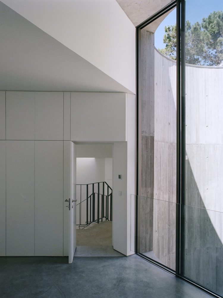 Enfamiljshus i betong med skjutdörrar i glas och utsikt över innergården