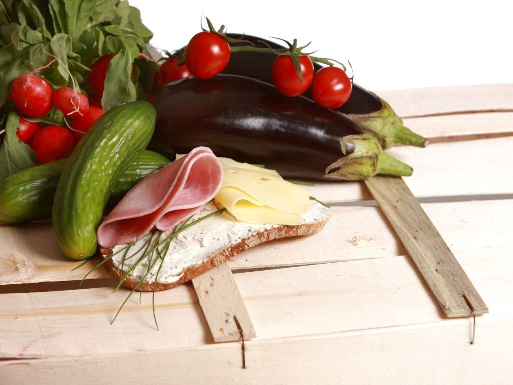bröd med färskost skinka purjolökost bredvid gurka och rädisor