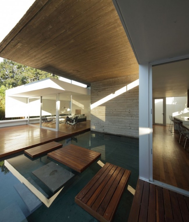 Modernt hus platt tak trädäck stegsten vatten damm glas vägg interiör