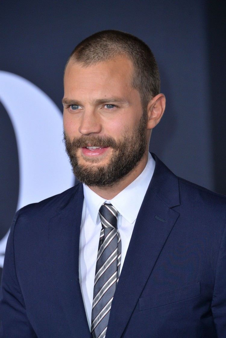 jamie dornan kort frisyr med tre dagars skägg och kostym för ett modernt utseende och outfit