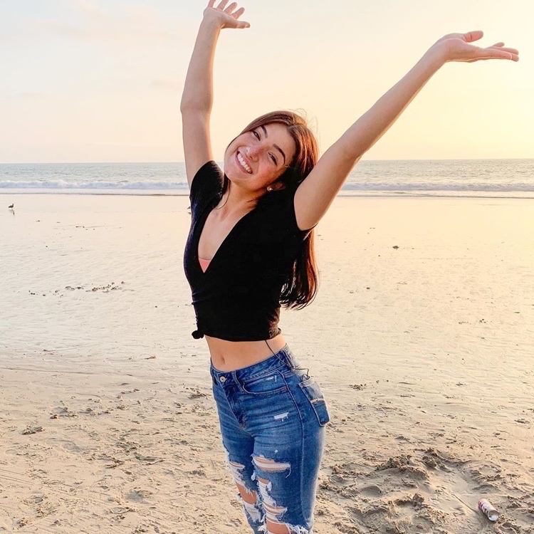 Charli D'Amelio med en croptop och jeans med hög midja på stranden