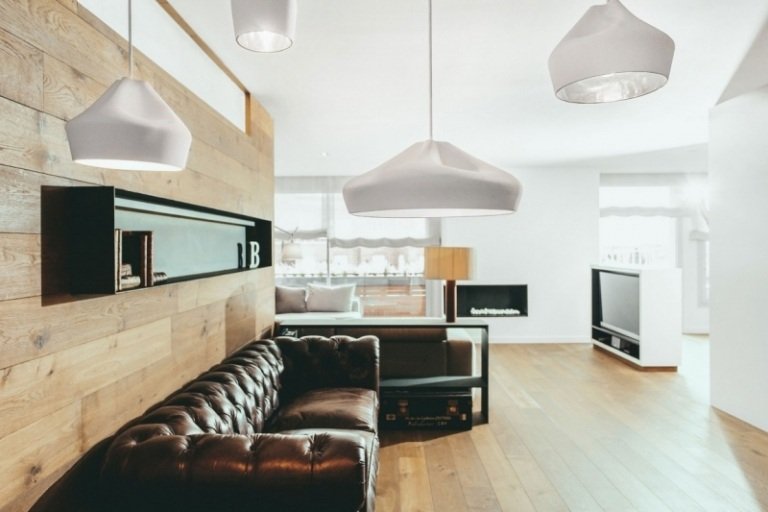 Chesterfield soffa -moderna-trä-golv-väggbeklädnad-hängande-ljus-öppna-utrymme-vit