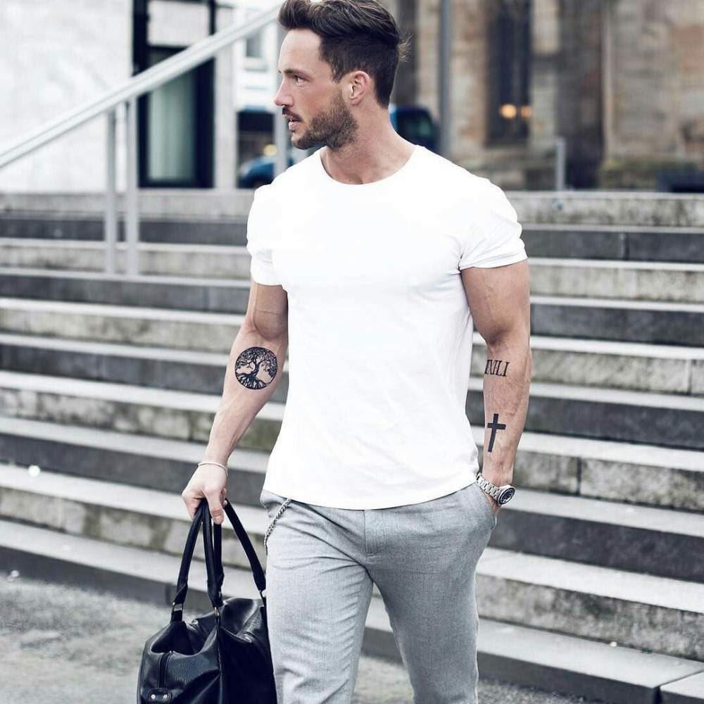 grå byxa med vit t-shirt och svart läderväska för en avslappnad look