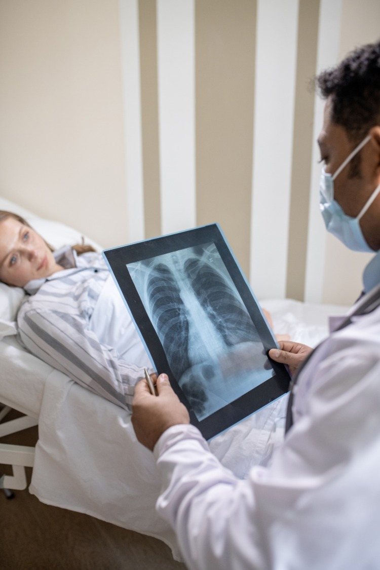 Läkaren tittar på lungröntgen av ung kvinna med covid 19