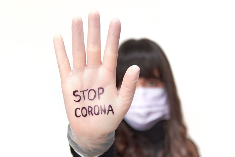 kvinna med skyddsmask och inskription stoppar coronaviruset på hennes hand