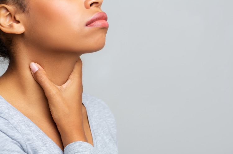 kvinnlig person som håller i nacken på grund av ont i halsen på grund av corona -virus