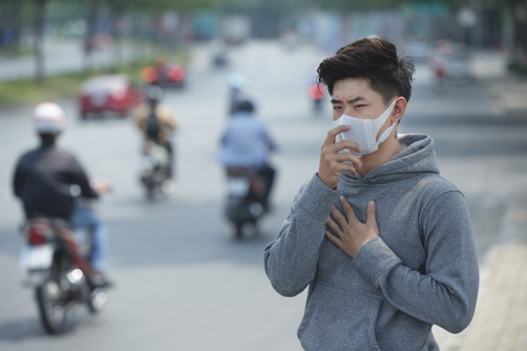 Kinas unga man med skyddsmask håller fast vid corona -bröstets effekter på bröstet