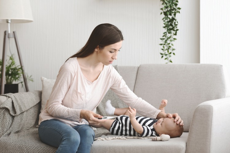 Bekymrad mamma testar sitt nyfödda barn med hög feber