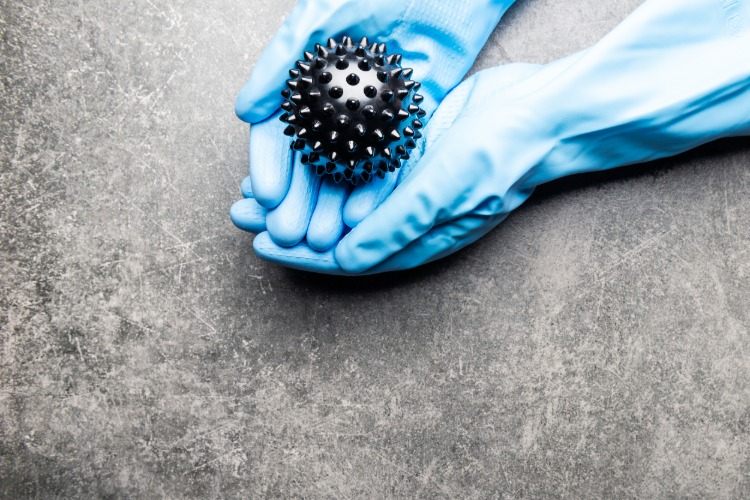 händer med gummihandskar håller symboliskt coronavirus i svart