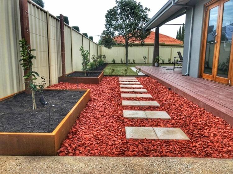 Höjdbädd i lågt cortenstål med rött grus i minimalistisk trädgårdsstil