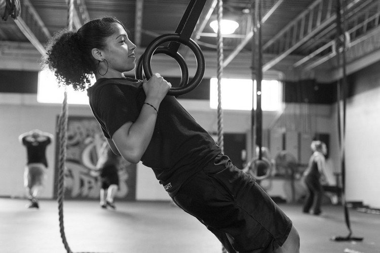kvinna som tränar med ringar i gymmet med utrustning och sportkläder