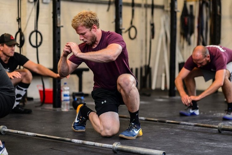 crossfit -tränare visar gruppövningarna med benen i gymmet