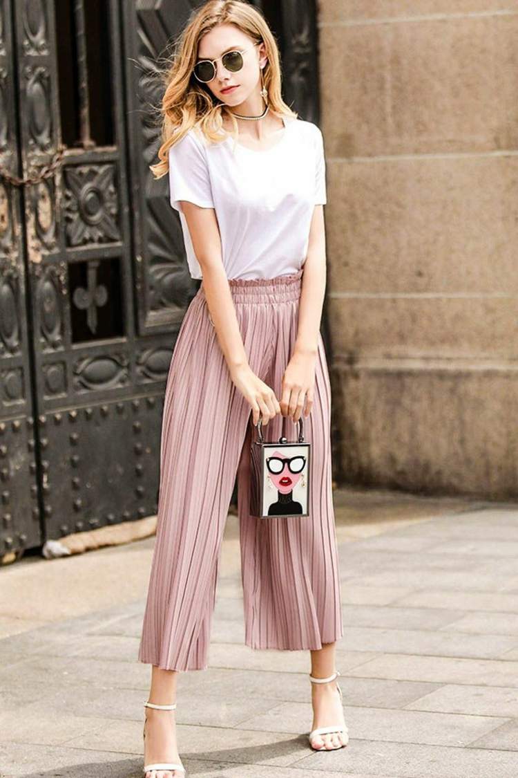 Plisserade culottes kombinerar pastellrosa t-shirt handväska blont hår modetrender