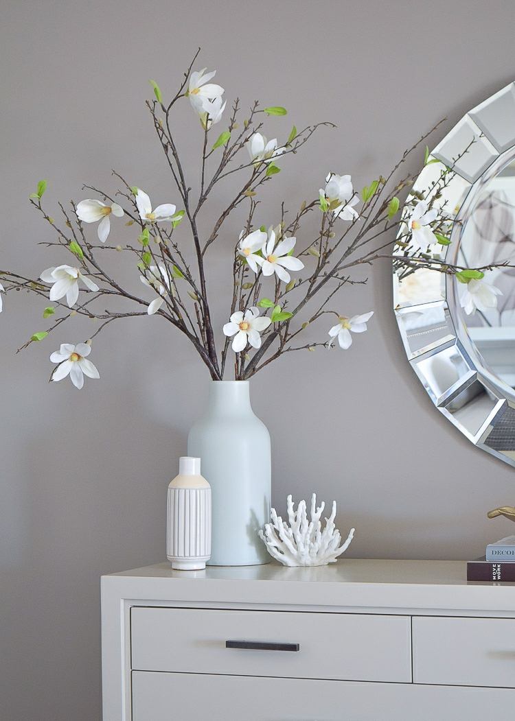 Vacker bukett med vita blommande grenar på en modern skänk