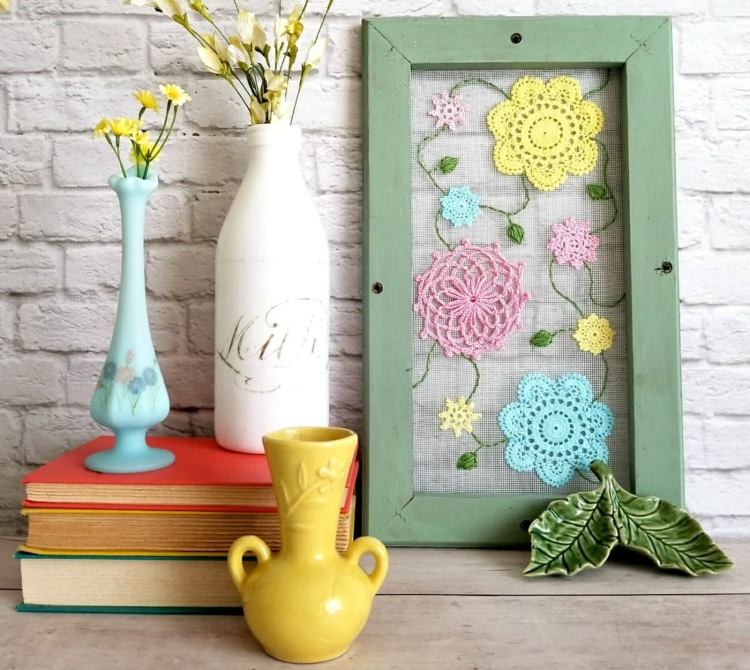 Virkade blommor i pastellfärger i en tavelram som vårdekoration