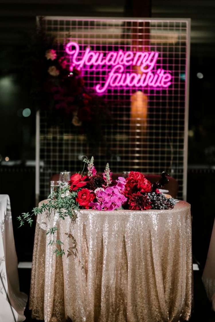 Glamorös bröllopsdekoration i guld med rosa neonljus i bakgrunden
