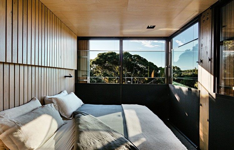 design stuga sluttande kust kust skog modern fjällstuga sovrum säng fönster utsikt solljus