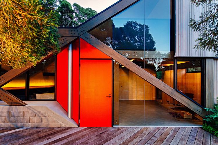 design fritidshus sluttande kust kust skog modern fjällstuga ovanlig form trä veranda entrédörr glasfönster