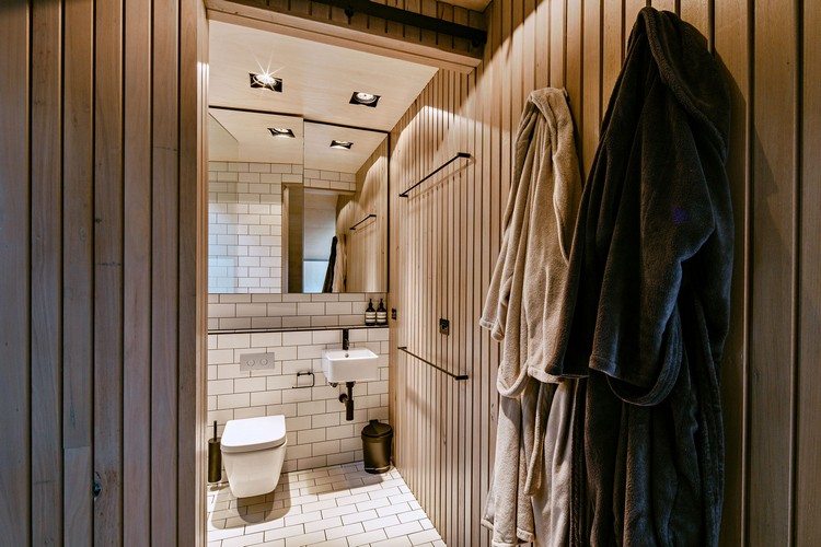 design fritidshus sluttande kust kust skog modern fjällstuga toalett spegel handfat liten badrock