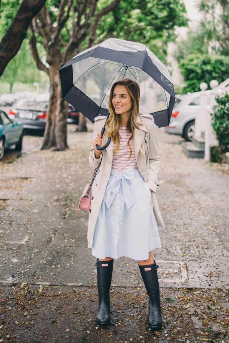 Söt kjol med gummistövlar och en trenchcoat för regndräkten
