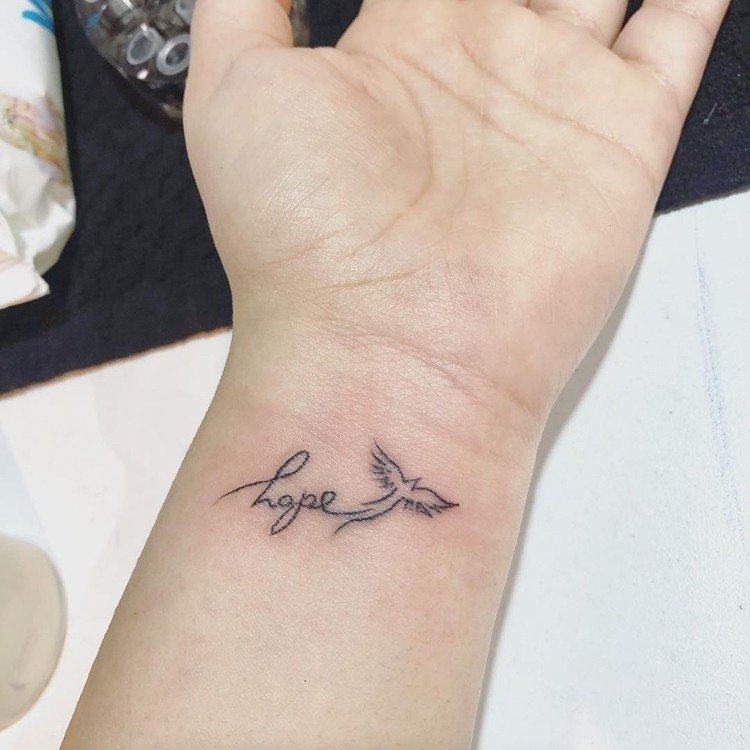 liten tatuering bokstäver fågel handled kvinna