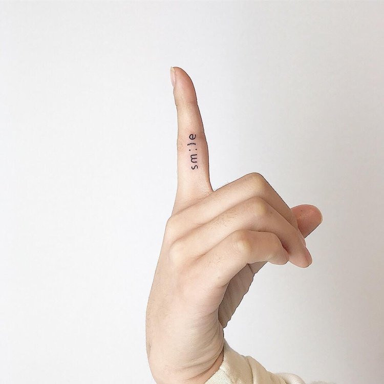 Mini tatuering finger bokstäver leende