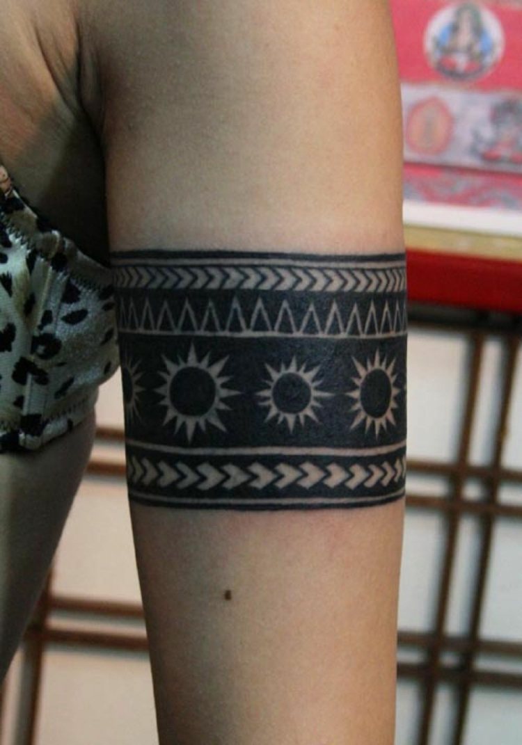 tatuering armband kvinna överarm bred iögonfallande geometriska figurer sol symbol