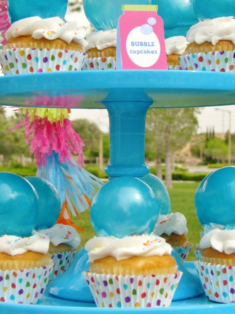 Blå bubblor och prickiga formar dekorerar cupcakesna för en fest